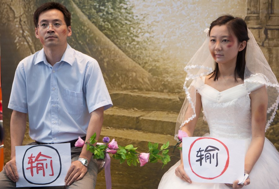 Two volunteers are using behavioral art to raise people's awareness of the domestic violence. Photo by Xinhua.