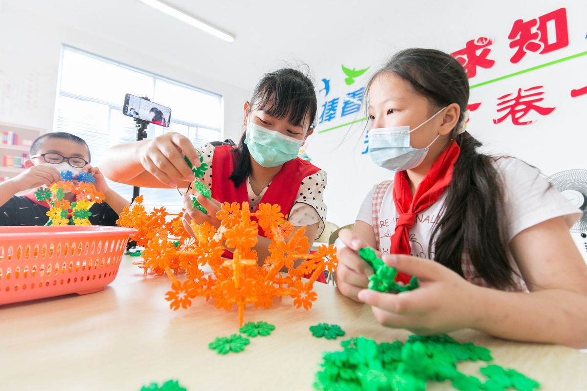 A volunteer teaches a children in a rural library in Rugao, Jiangsu province. Photo by Xinhua.