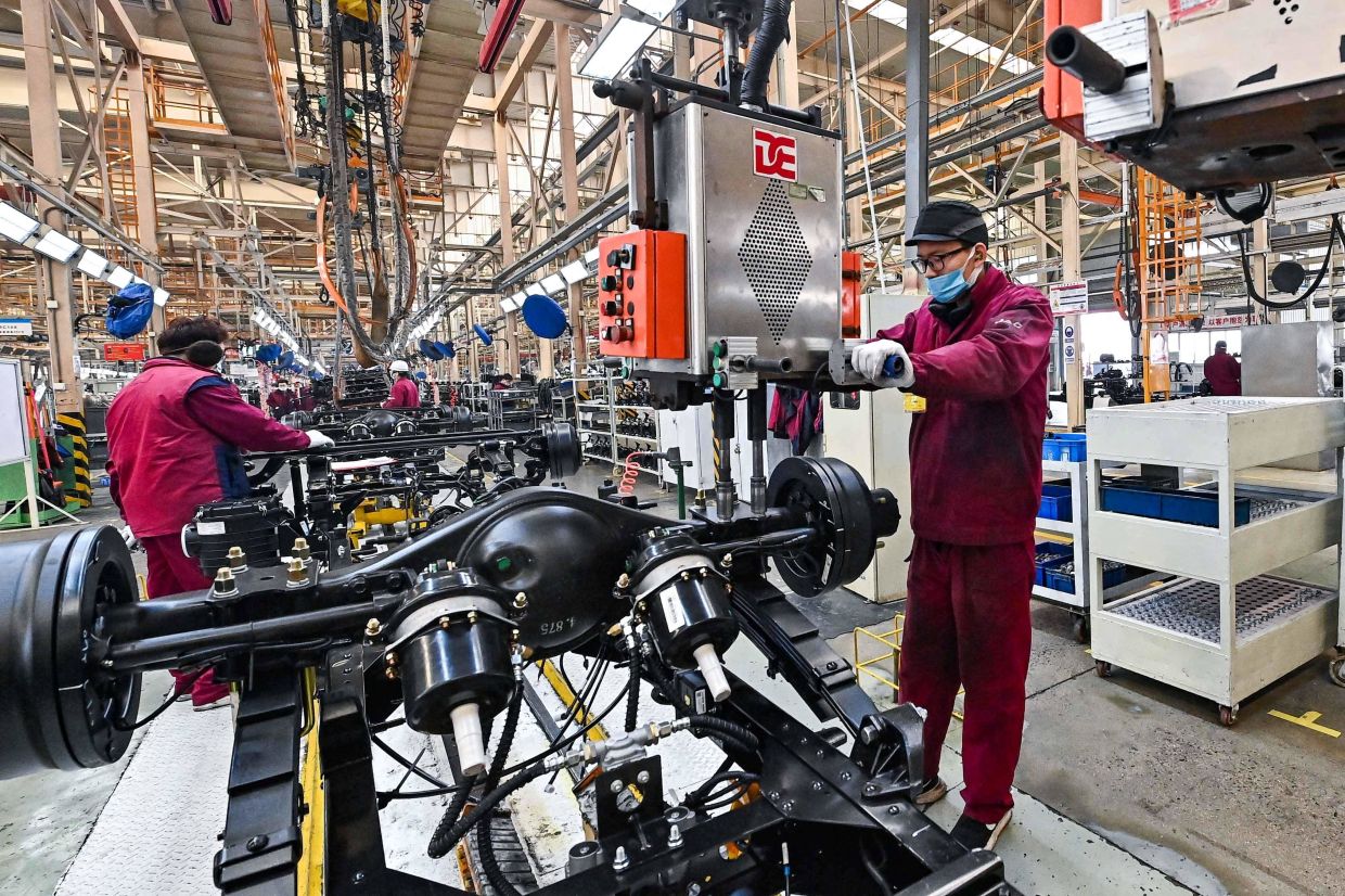 Employees work on a truck assembly line at a factory for the vehicle manufacturing company Jianghuai Automobile Group Corp. (JAC) in Qingzhou in eastern China's Shandong province. Photo by Xinhua.