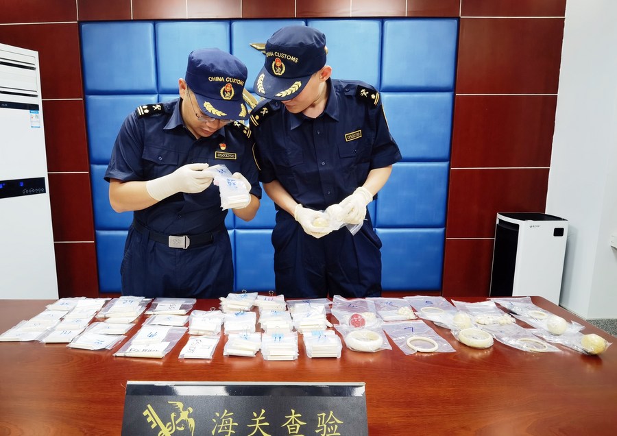 Staff members of customs check ivory products and red coral products seized in inbound parcels, in Taiyuan, north China's Shanxi Province. Photo by Ni Song/Xinhua.

