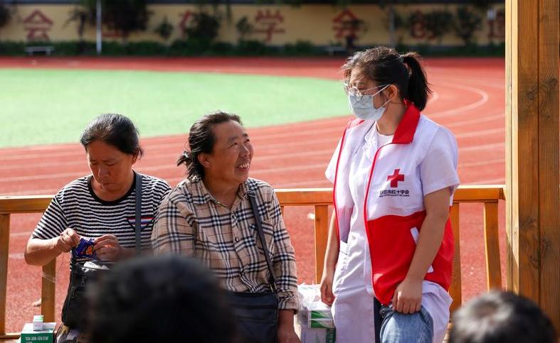 A staff member of Red Cross Society of China (RCSC) talks with residents at a temporary shelter in Shulan No.3 Middle School in Shulan City, northeast China's Jilin Province. Photo by Xinhua/Yan Linyun.