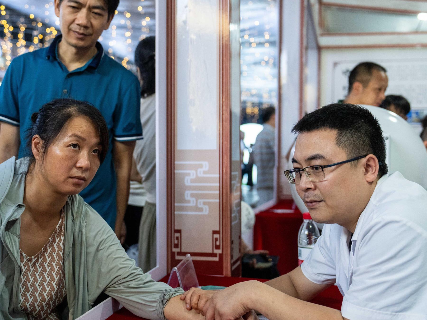 A medical worker (R) takes a citizen's pulse at a night traditional Chinese medicine clinic in Changning City, central China's Hunan Province. Photo by Xinhua/Chen Sihan.